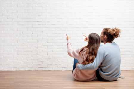 幸福的年轻夫妇坐在他们新房子的地板上。 爱和搬家的概念。