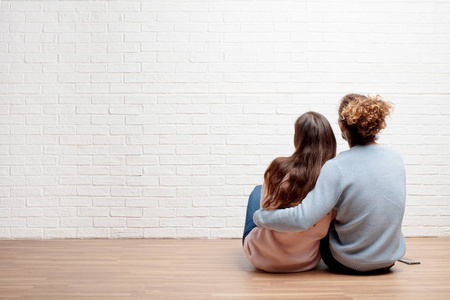 幸福的年轻夫妇坐在他们新房子的地板上。 爱和搬家的概念。
