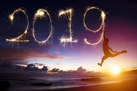 新年快乐2019.男人在海滩上跳跃和画画