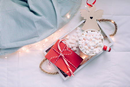 新年或圣诞节平躺顶景与热可可咖啡巧克力与棉花糖杯圣诞节庆祝红色礼物盒在木制托盘在床上与灯。 概念博客社交媒体2019