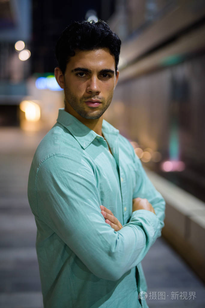 年轻英俊的西班牙人在夜间探索城市街道