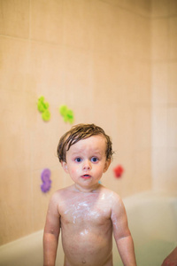 一个患皮疹的小男孩站在浴缸里，身体上的凝胶在室内