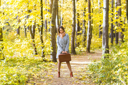 秋天, 季节和人概念秋天公园与复古手提箱站立的年轻妇女
