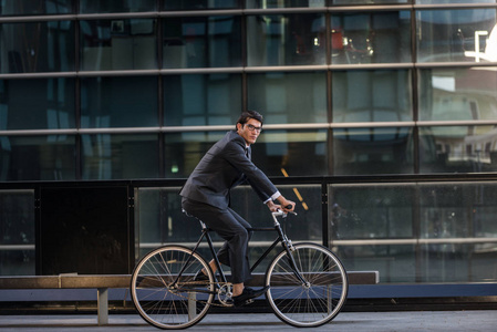 年轻的英俊男子，穿着商务服驾驶自行车企业商人肖像，关于商业流动性和生活方式的概念