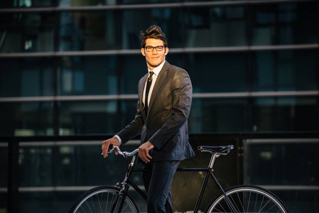 年轻的英俊男子，穿着商务服驾驶自行车企业商人肖像，关于商业流动性和生活方式的概念