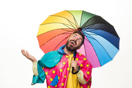 在白色背景查出的有彩虹色的雨伞的野蛮胡子男子。下雨的天气。云雨伞。下雨的概念。秋天的心情和天气温暖, 阳光明媚, 下雨是可能的