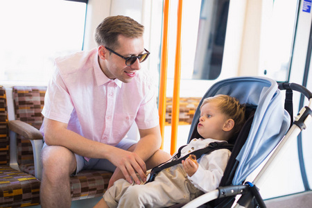 小可爱的男孩坐在公共汽车里，坐在他幸福的父亲旁边