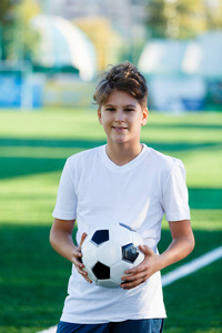 可爱的小男孩穿着白色蓝色运动服，在球场的绿草上拿着古典。 足球游戏训练爱好概念。 副本空间