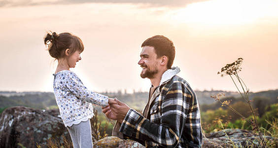 爸爸和女儿在日落时走在大自然中，家庭重视家庭关系