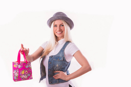 年轻活泼的金发女郎戴着帽子的肖像，手里拿着一个白色背景的小包