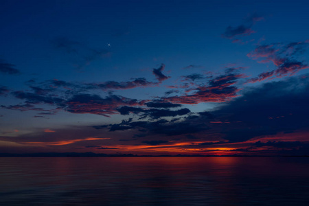 美丽的海景，夕阳的天空和云彩进入黄昏与第一颗星。