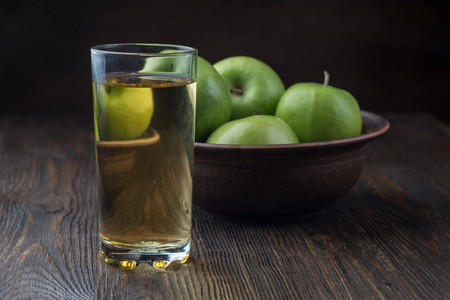 杯子里的苹果汁，木制背景的粘土碗里的苹果