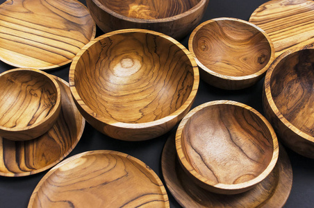 黑色背景下厨房碗盘的木制器皿。 天然菜肴的概念是一种健康的生活方式。 木质环保木器的质地