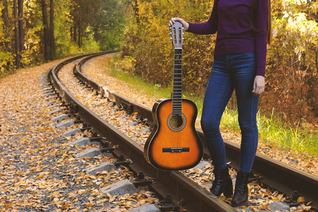 秋天公园里有吉他的漂亮女孩。 带吉他的少年在铁路上。