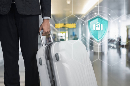 旅游保险盾牌保护旅行在虚拟屏幕上对商人和手提箱在机场的背景下保险在线保险数字技术的概念。
