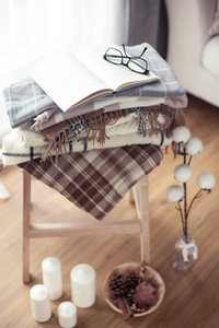 格子呢。 秋天舒适的内部。 在木椅上是一叠温暖的毯子。 蜡烛留下锥形篮子肉桂。 书和眼镜。 秋天。