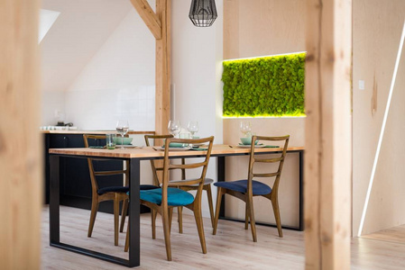 现代餐厅的木制桌子。 阁楼上现代明亮的公寓。 厨房有黑色厨房橱柜
