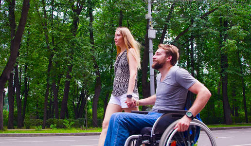 年轻的残疾人男子在公园散步与他的妻子