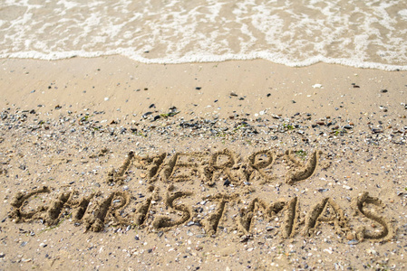 圣诞快乐写在热带海滩沙滩复制空间。 假日概念