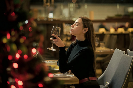 完美的葡萄酒。酒吧顾客坐在咖啡厅饮酒。长头发的女孩喝红酒。漂亮女人和酒杯在餐厅休息。在酒馆等待的女性品酒师的日期会议