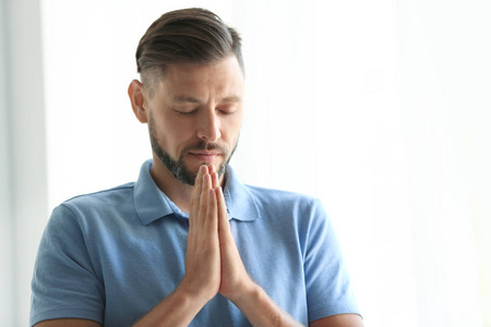 男人双手紧握在一起，在光明的背景下祈祷。 文本空间