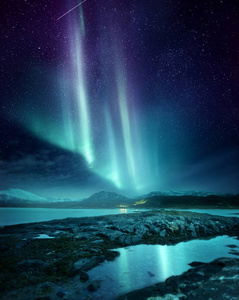 一个壮观的北极光极光展示照亮了挪威北部的夜空。北极圈内狩猎北极光的热门目的地。照片合成。