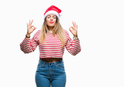 年轻漂亮的女人戴着圣诞帽，在孤立的背景上放松，闭着眼睛微笑，用手指做冥想手势。 瑜伽概念。