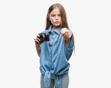 年轻漂亮的女孩用老式相机在孤立的背景上拍照，手指指向相机，并向你手势正面和自信的手势。