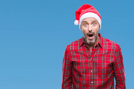 中年老人戴着圣诞帽，在孤立的背景下害怕和震惊，惊讶的表情，恐惧和兴奋的脸。