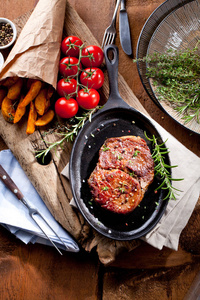 中罕见的烤牛肉与土豆在黑石背景。 俯视图平躺