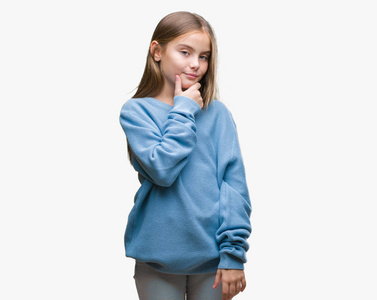 年轻漂亮的女孩穿着冬天的毛衣，在孤立的背景上，自信地看着相机，微笑着交叉的手臂和举起的手在下巴上。 积极思考。