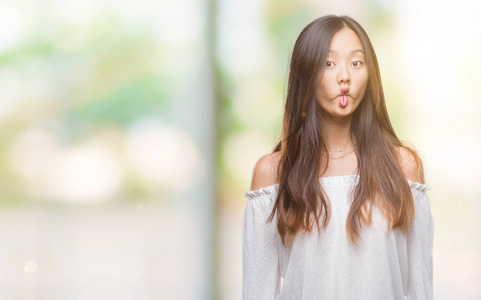 年轻的亚洲女人在孤立的背景下，使鱼的脸与嘴唇疯狂和滑稽的姿态。 有趣的表情。