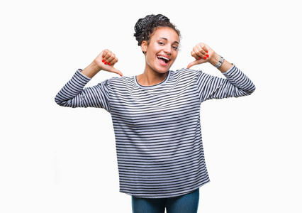 年轻的辫子非裔美国女孩穿着毛衣，在孤立的背景下，自信地微笑着，用手指指着自己，骄傲和快乐。
