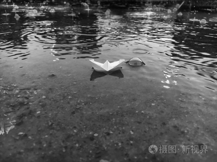 雨天小纸船漂浮在水坑里 黑白怀旧场景.