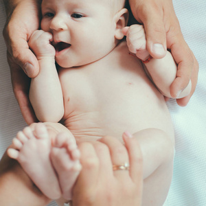关心的手。父母手里的新生婴儿。新生婴儿给予身体按摩。身体皮肤护理。保持宝宝的皮肤健康。在我们的关怀中感受爱