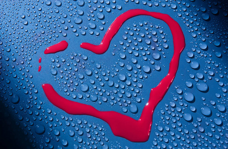 在被水滴包围的玻璃表面上以红色油漆绘制心形。 爱的宣言。 特写镜头。 背景。