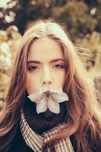 免费春季时间。美丽的女人与花朵在 mouht。愉快的美丽的女孩在毛衣户外在美丽的秋天天