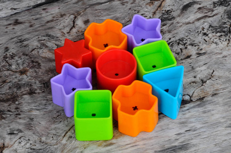 s toy blocks in various shapes made of plastic on wood grain bac