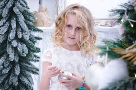 可爱的小女孩装饰的圣诞树由小玩意在家里
