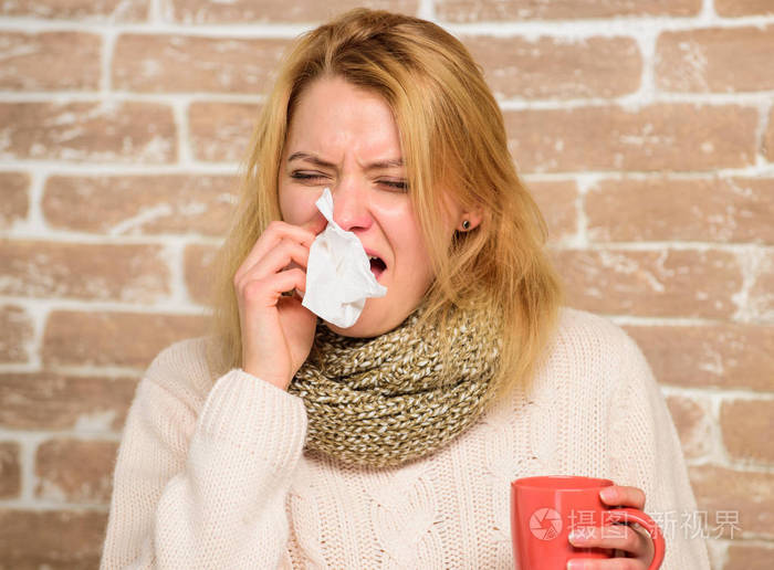 戴围巾的女孩拿着茶杯和纸巾. 流鼻涕和其他感冒症状.