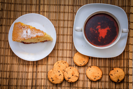 梅饼干蛋糕，一杯热茶，放在稻草床上用品上，篮子里放着巧克力饼干