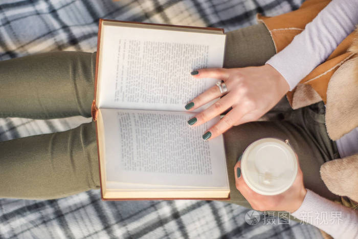 手里拿着书和咖啡的女人. 女孩在复古毯子上看书. 秋天概念形象.