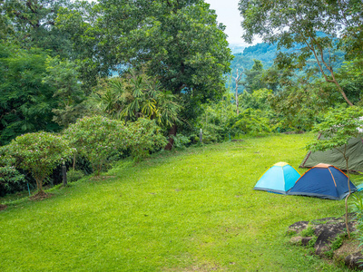 在绿草上露营蓝色帐篷，山和蓝天景色。