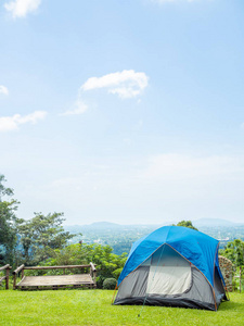 露营蓝色帐篷在绿草上与山和蓝天景观垂直风格与复制空间。