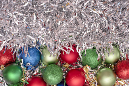 银色金属箔背景下的绿色蓝色和红色的圣诞玩具