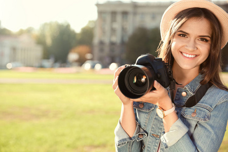 年轻的女摄影师拿着专业的相机在街上。 文本空间