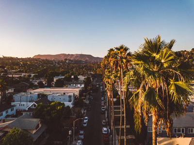 贝弗利山街与棕榈树在洛杉矶日落与好莱坞标志在地平线上。