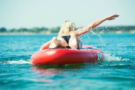 年轻的女人在桨板上游泳。水上运动积极的生活方式。