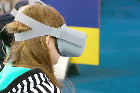 可爱的小女孩在虚拟现实眼镜里玩游戏。戴着网络空间眼镜的女孩花时间在虚拟现实中。