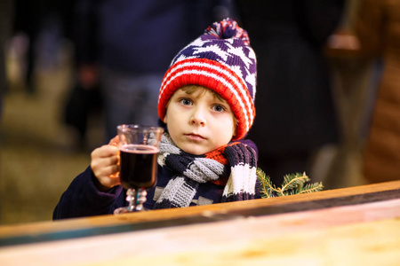 可爱小孩男孩端杯热腾腾的热巧克力或儿童拳。在德国的圣诞市场上快乐的孩子。学龄前孩子的冬天衣服变暖手杯和喝蛋酒